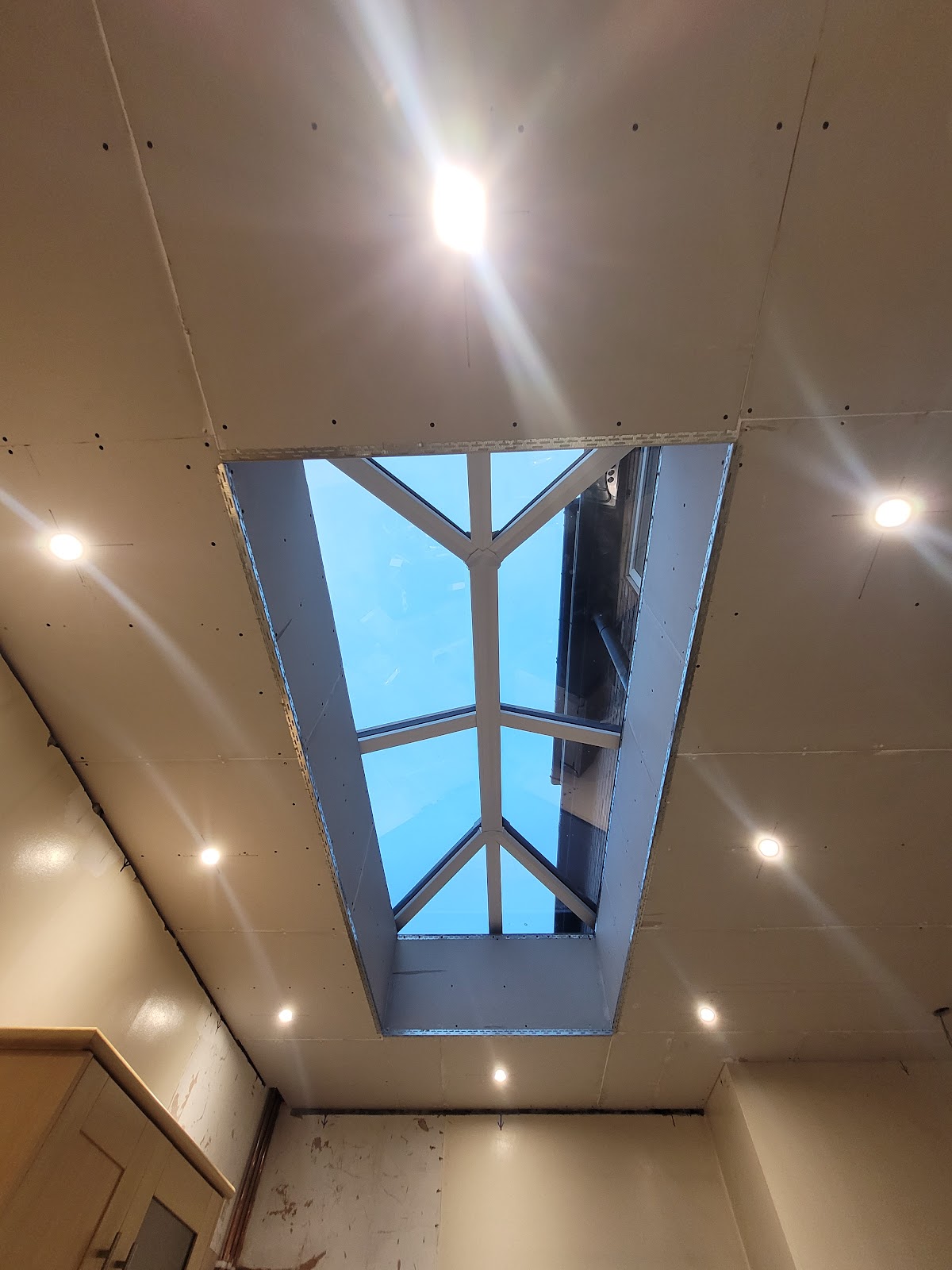 Looking up through a newly fitted roof lantern, with the plasterboard reveal finished around the opening