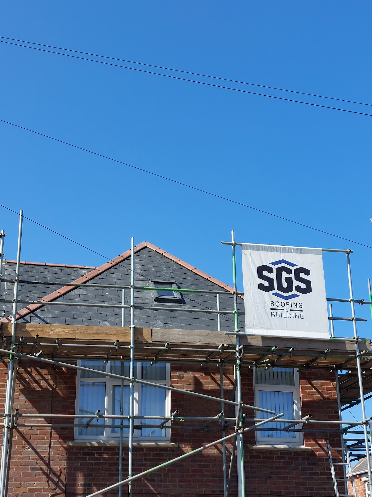 The SGS Roofing and Building banner on the scaffold beside a finished slate gable in North Shields